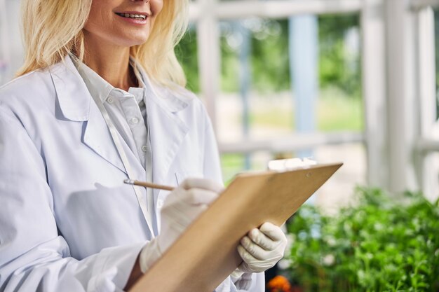 Foto ritagliata di una donna con un sorriso compiaciuto che tiene in mano un blocco per appunti