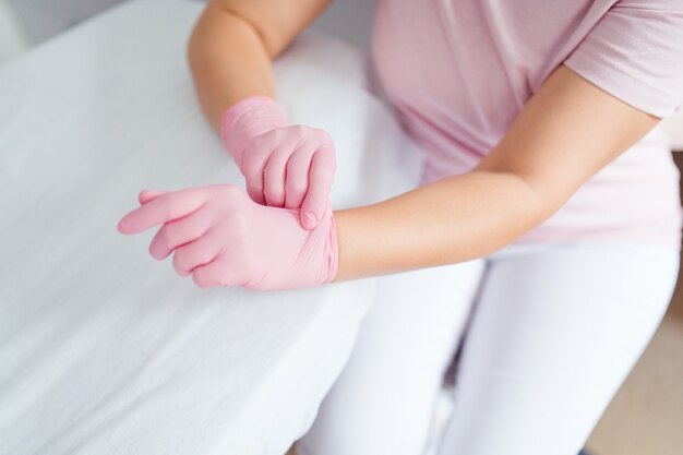 Foto ritagliate donna cosmetologo mani in guanti di gomma rosa pronti per il lavoro