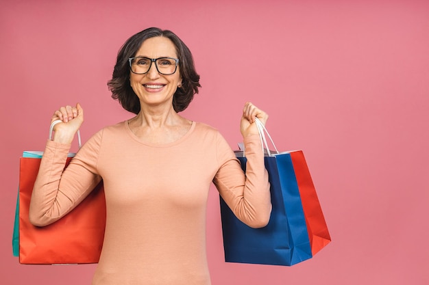 Foto ritratto di donna matura senior pensionato di età compresa tra donna avendo pacchetti dopo lo shopping nei negozi il venerdì nero isolato su sfondo di colore rosa.