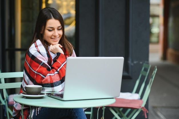 Foto ritratto di splendida donna attraente che lavora al computer portatile digitando seduto al bar a bere caffè