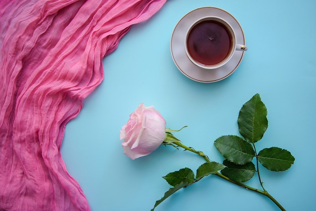 Foto romantica di tè, tessuto rosa e rosa su sfondo blu