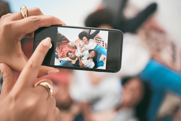 Foto scattata al telefono sopra un gruppo di amici sdraiati sul pavimento insieme divertendosi e legando Giovani diversi e liberi mentre posano per una foto per i social media o semplicemente per catturare un momento felice