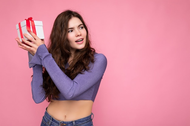 Foto scattata di bella donna giovane riccia bruna felice isolata su sfondo rosa