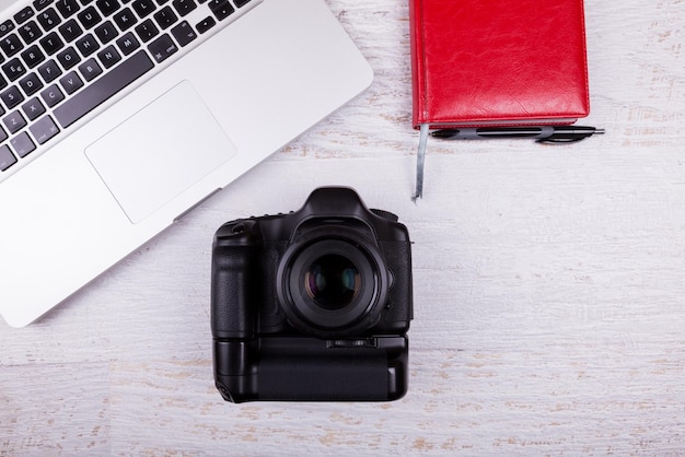 Foto sopra la fotocamera DSLR e laptop su sfondo di legno