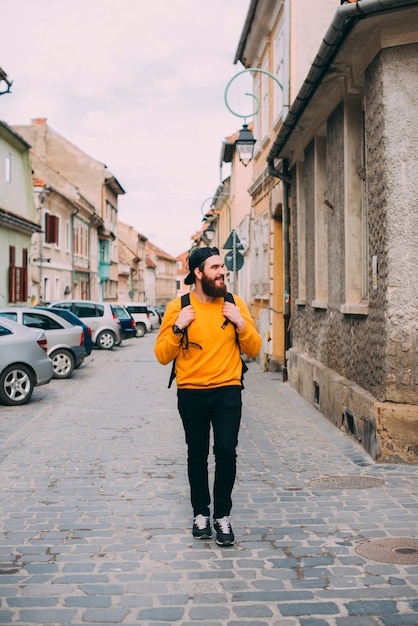 Foto un turista maschio barbuto che cammina su vecchie strade europee.