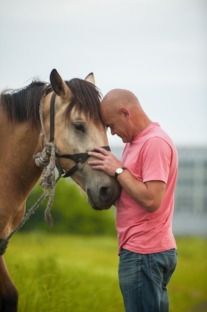 Foto uomo calvo cammina con un cavallo nel campo