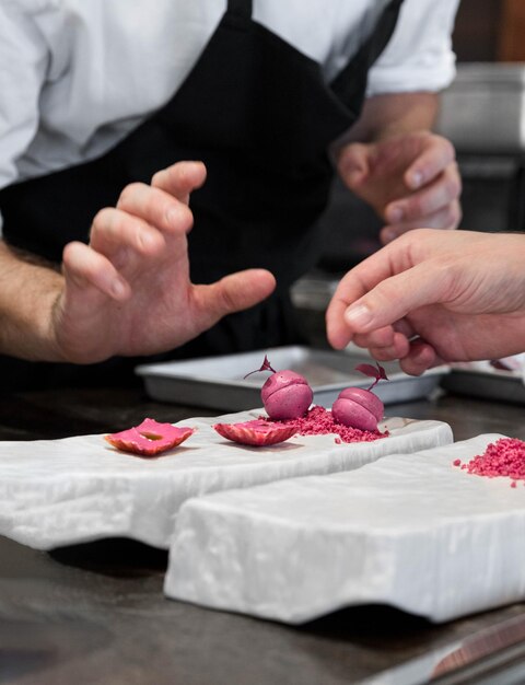 Foto verticale con due mani di cuochi che preparano un piatto gastronomico