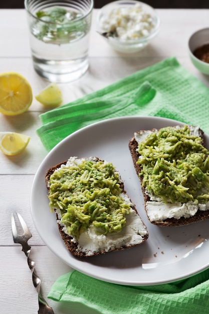 Foto verticale dei panini dell&#39;avocado con la ricotta sul piatto bianco