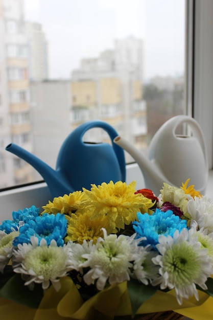 Foto verticale del balcone di casa con bouquet di fiori e piante a naso lungo annaffiatoi sul davanzale