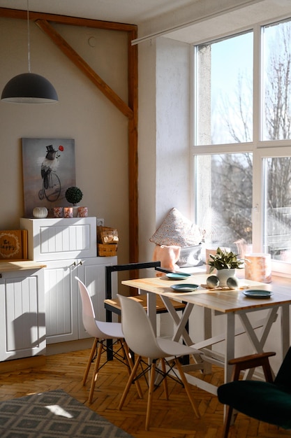 Foto verticale della cucina con elementi in legno facciate bianche pavimento in parquet ampia finestra