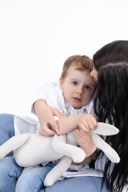 Foto verticale della madre seria che tiene i bambini stretti del figlio spaventato che balbettano l'esperienza traumatica del problema