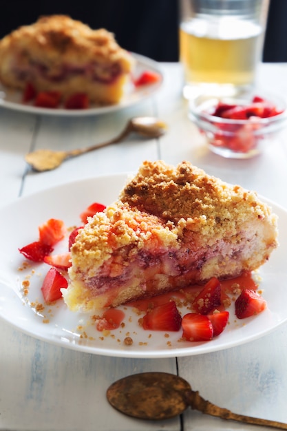 Foto verticale della torta della briciola della fragola con le fette di bacche sul piatto bianco