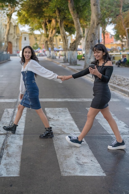 Foto verticale di donne che attraversano la strada insieme mentre utilizzano un cellulare