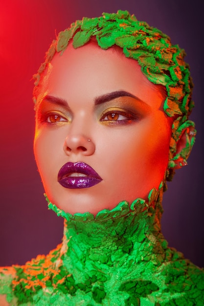 Foto verticale di una donna caucasica sensibile con trucco multicolore creativo in studio