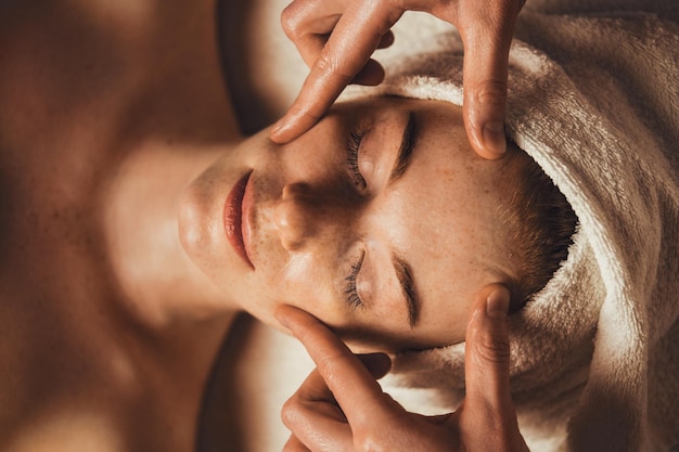 Foto vista dall'alto del cosmetologo che fa un trattamento di massaggio facciale per il viso della donna paziente al salone spa Trattamento di bellezza Bellezza del viso Pelle di bellezza