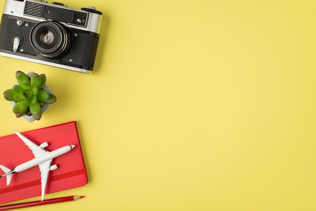 Foto vista dall'alto della penna della fotocamera della pianta e del modello aereo sul diario rosso su sfondo giallo pastello isolato con copyspace