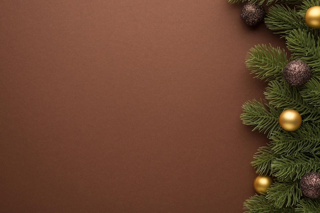 Foto vista dall'alto di palline di albero di natale dorate e marroni su rami di pino su sfondo marrone isolato con copyspace