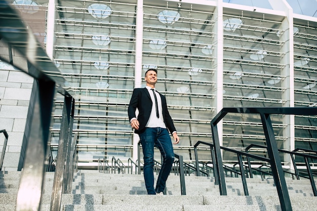 Foto vista laterale di un uomo d'affari fiducioso in abbigliamento formale che guarda lontano mentre si cammina giù per le scale