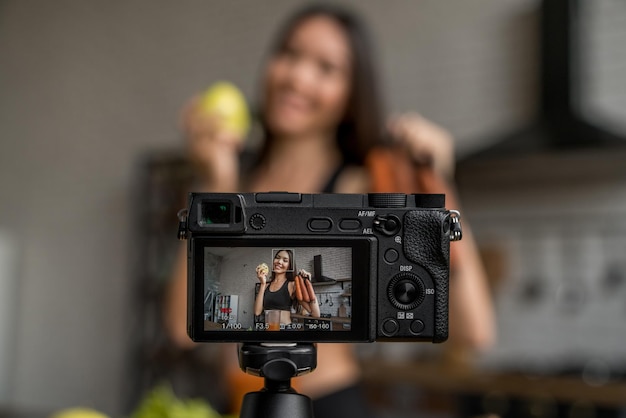 Fotocamera che mostra la donna con frutta e verdura in mano mentre la donna registra video