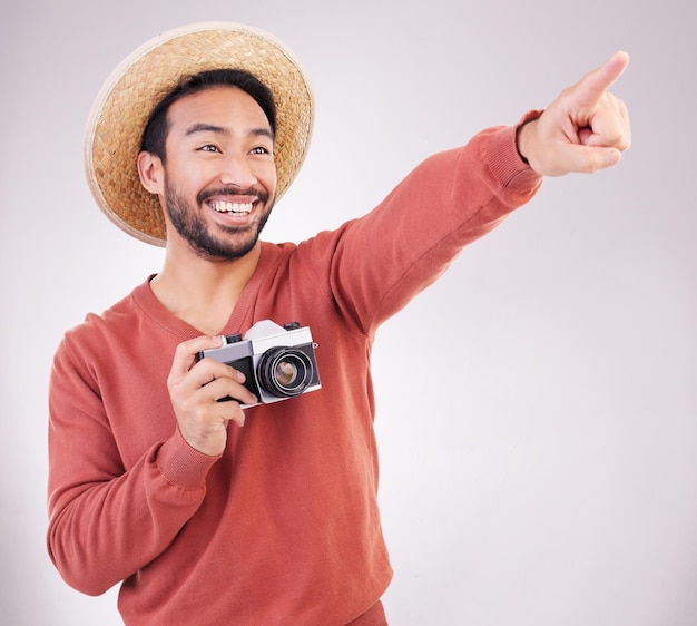 Fotocamera da viaggio e uomo eccitato che punta a vista in studio in vacanza con divertimento avventuroso e sfondo bianco Sorriso scoperta e turista felice in vacanza fotografo in viaggio con felicità