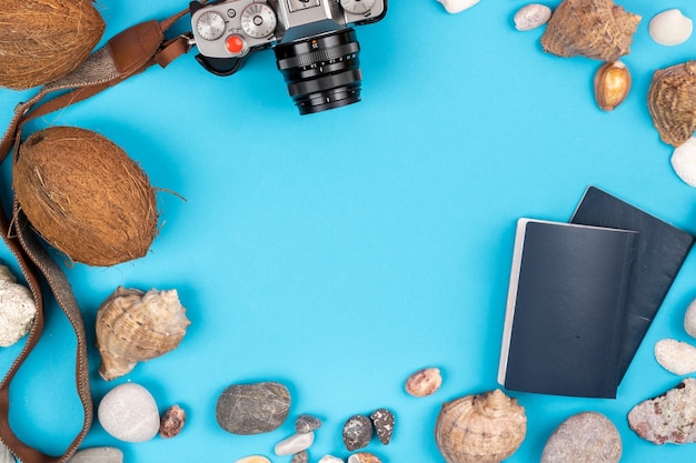 Fotocamera, noci di cocco, conchiglie e documenti su sfondo blu. Sfondo per il viaggiatore