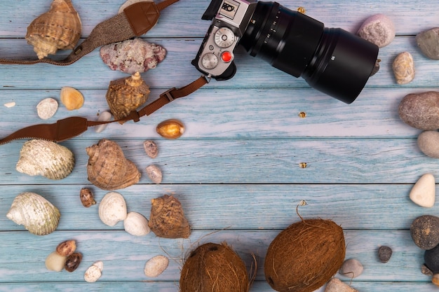 Fotocamera, noci di cocco e conchiglie su uno sfondo di legno blu. Tema marino