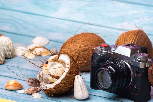 Fotocamera, noci di cocco e conchiglie su uno sfondo di legno blu. Tema marino.