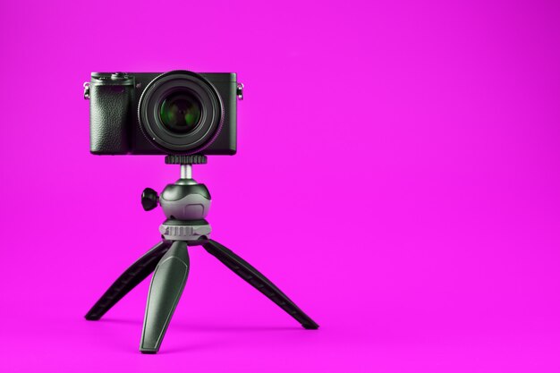 Fotocamera professionale su un treppiede, su uno sfondo rosa. Registra video e foto per il tuo blog o rapporto.