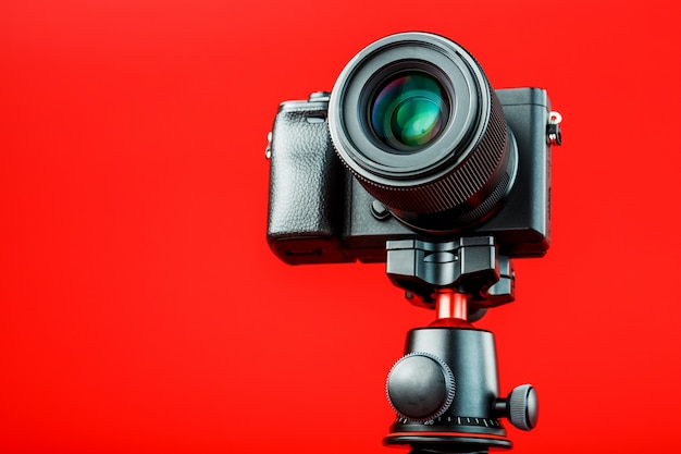 Fotocamera professionale su un treppiede, su uno sfondo rosso. Registra video e foto per il tuo blog, reportage