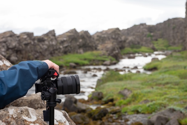 Fotocamera sul treppiede con fiume sfocato