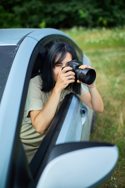 Fotografa donna seduta in macchina e fotografando un paesaggio di campo di fiori, donna di viaggio scatta foto, spazio per il testo
