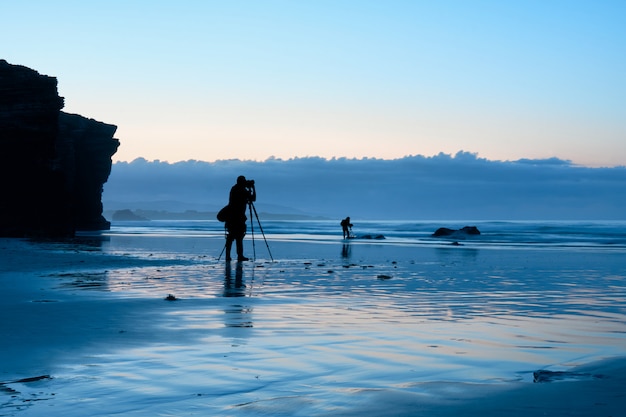 Fotografi che lavorano su una spiaggia durante l'ora blu