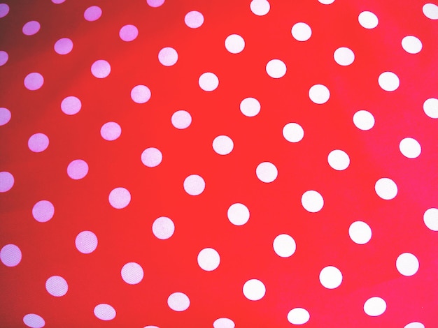 Fotografia completa di polka bianca punteggiata su tessuto rosso