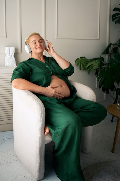Fotografia completa di una donna incinta che trascorre del tempo in casa