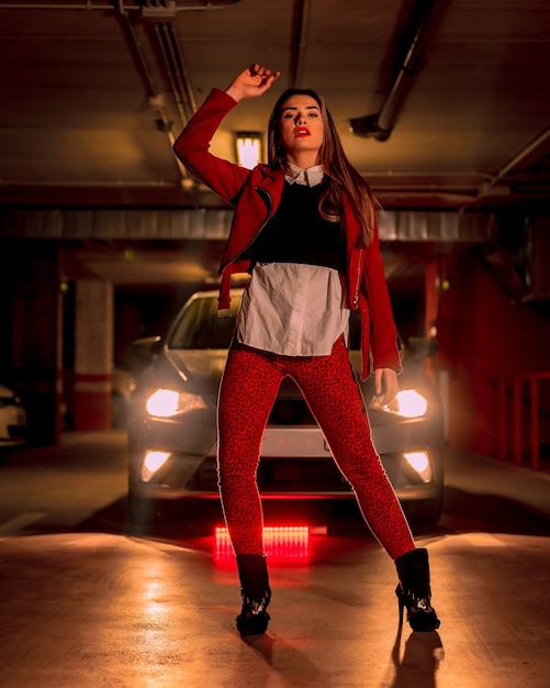 Fotografia con neon rosso davanti a un'auto in un parcheggio. Ritratto di una donna caucasica bionda abbastanza giovane