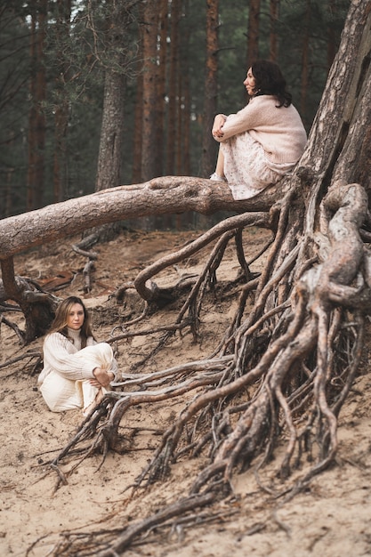 Fotografia concettuale di brune tra le radici della foresta belle ragazze siedono alle radici degli alberi e ...