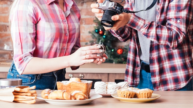 Fotografia di cibo. Lavoro di squadra. Uomo con assistente donna che scatta foto di torte e pasticcini freschi fatti in casa.