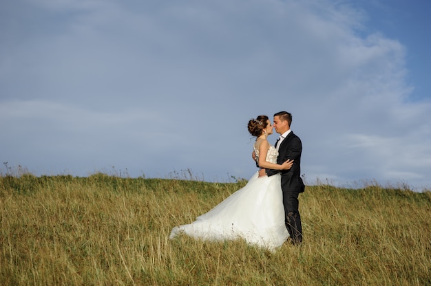Fotografia di matrimonio in montagna. Lo sposo abbraccia la sposa. Spazio libero.