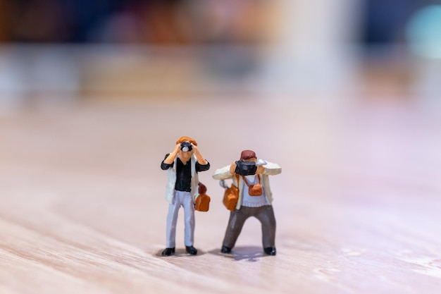 Fotografia di persone in miniatura che tiene una macchina fotografica e copia lo spazio per il testo