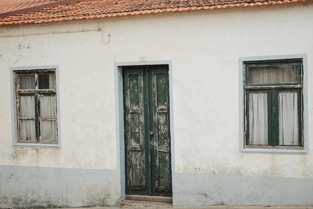 Fotografia di una vecchia casa con una porta e finestre verdi in Portogallo