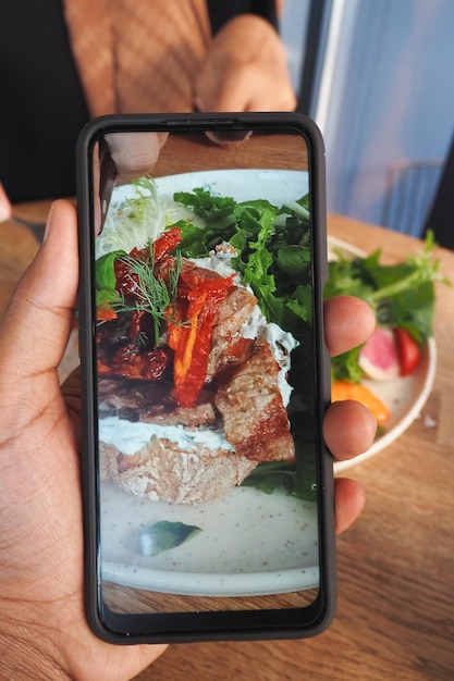Fotografia mobile di un delizioso pasto su un tavolo da pranzo in legno