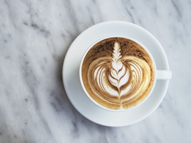 Fotografia piana di caffè con bella arte del latte su fondo di marmo bianco.