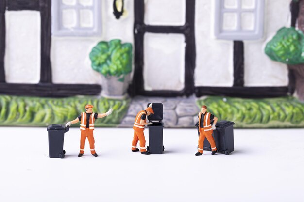 Fotografia selettiva di giocattoli per la raccolta dei rifiuti davanti a una casa in ceramica