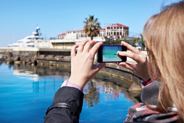 Fotografie della ragazza su una spiaggia e sul molo del telefono cellulare