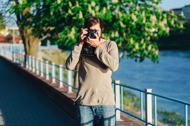 Fotografo alla moda in giro per la città con una macchina fotografica retrò