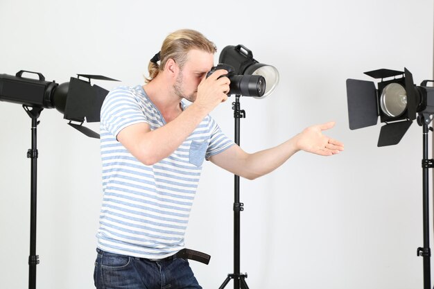 Fotografo bello con la macchina fotografica al lavoro sullo sfondo dello studio fotografico
