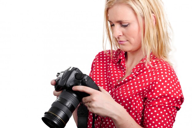 Fotografo biondo grazioso della donna con la macchina fotografica, su bianco