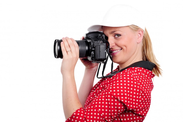 Fotografo biondo grazioso della donna con la macchina fotografica, su bianco