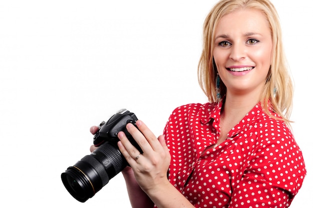 Fotografo biondo grazioso della donna con la sua macchina fotografica, su bianco