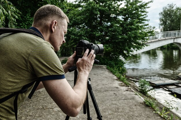 Fotografo che regola la macchina fotografica sul treppiede